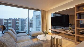 A modern living room with a large window, a flat-screen TV, a sofa, a coffee table, and a bookshelf.
