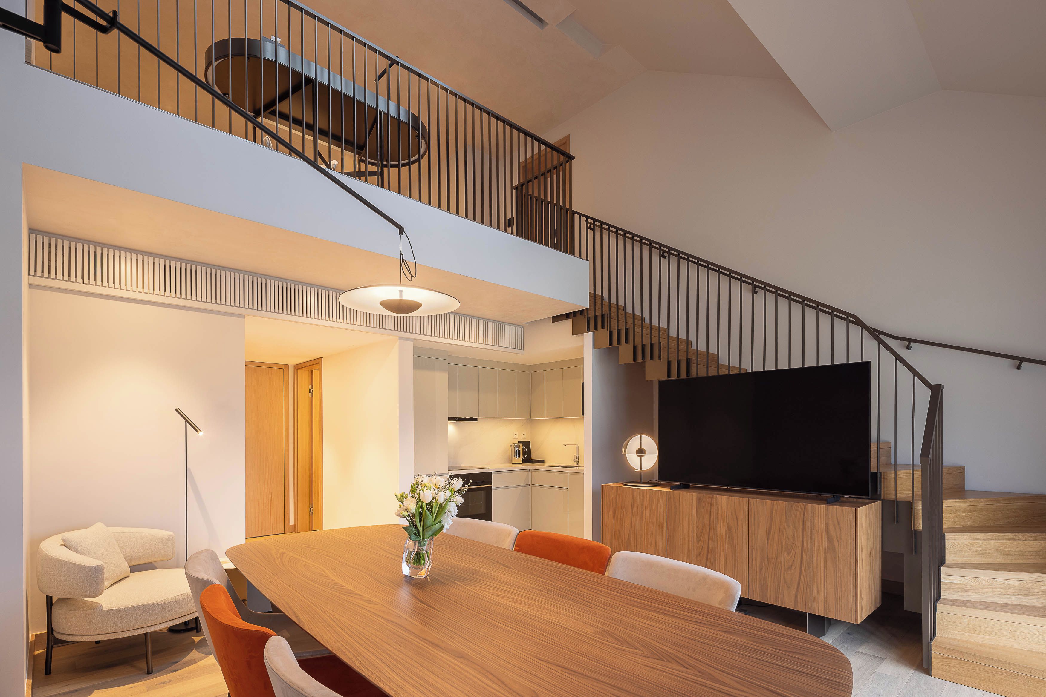 A modern interior with a dining area, kitchen, and a staircase.