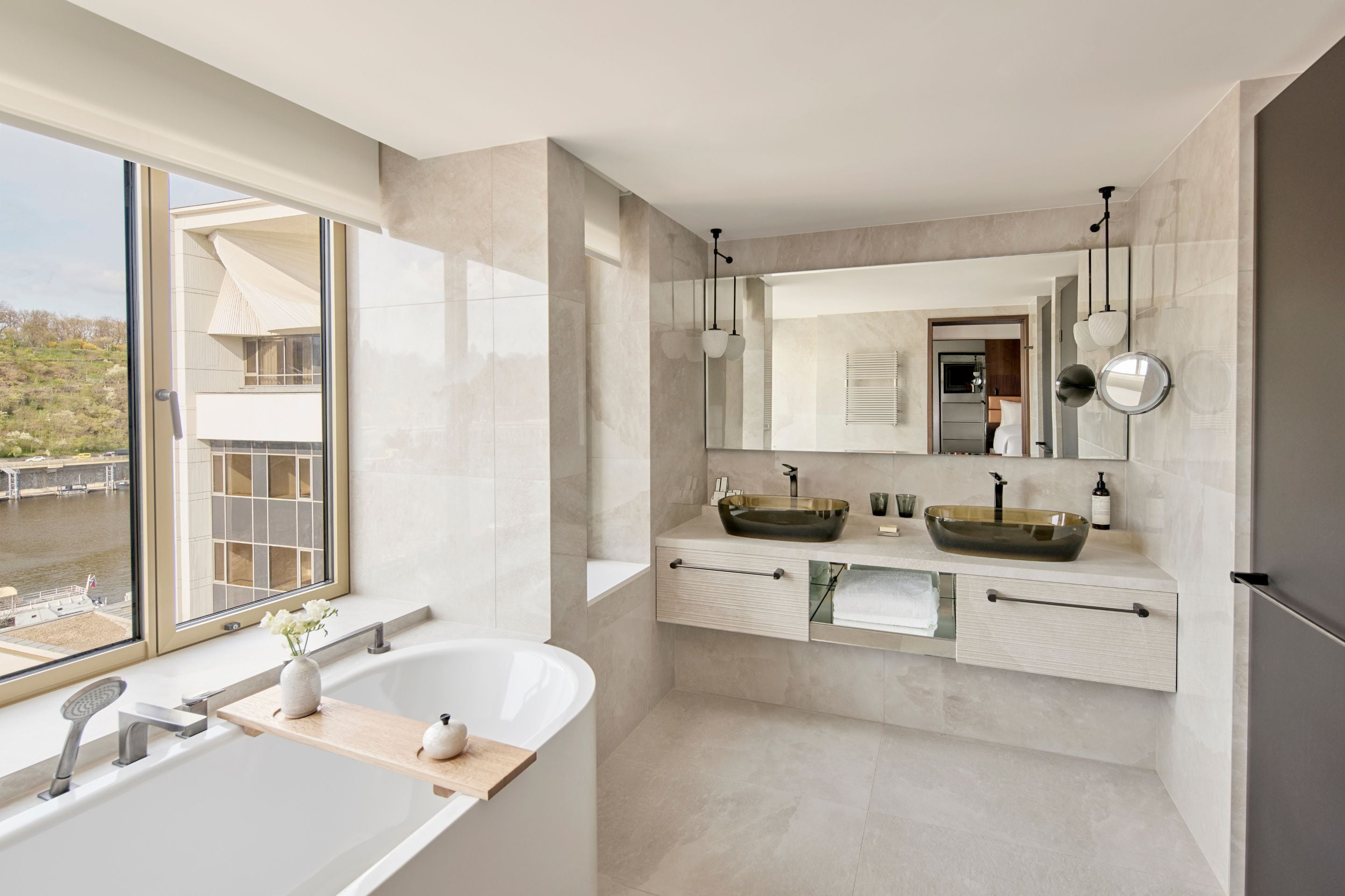 A modern bathroom with a large bathtub, two sinks, and a large mirror.