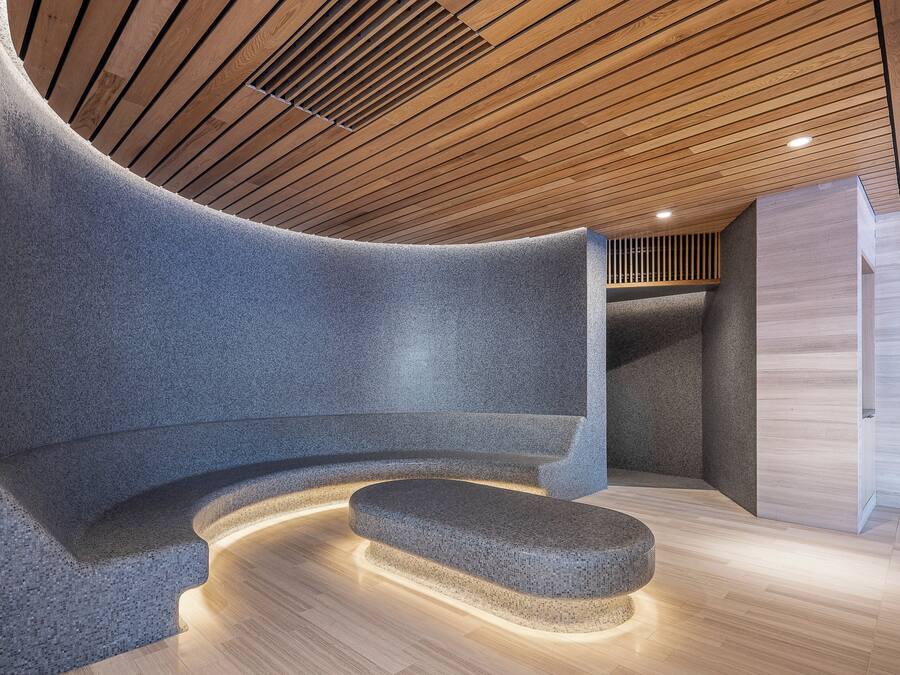 A modern interior with a curved seating area, wooden ceiling, and a stone bench.