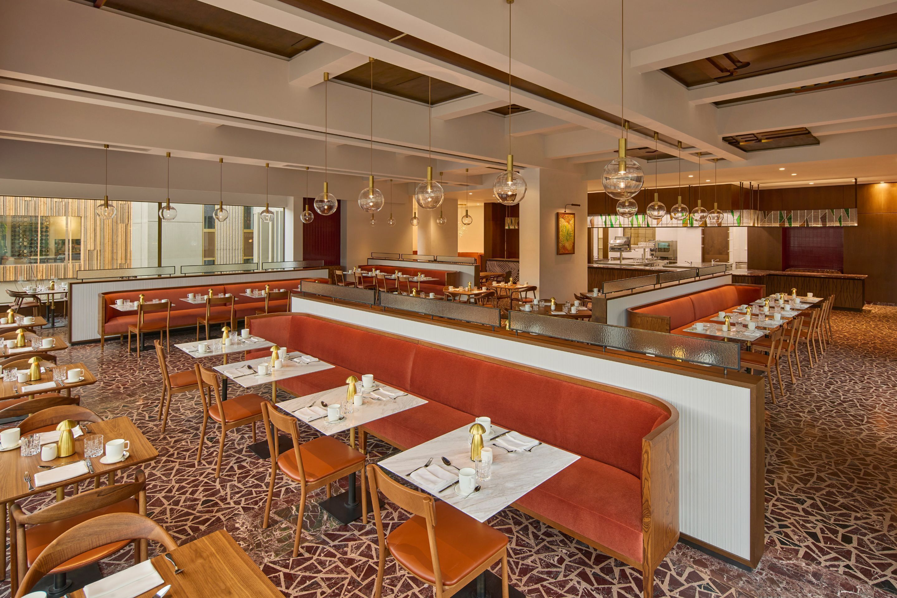 A modern restaurant with a central bar, booths, and tables.