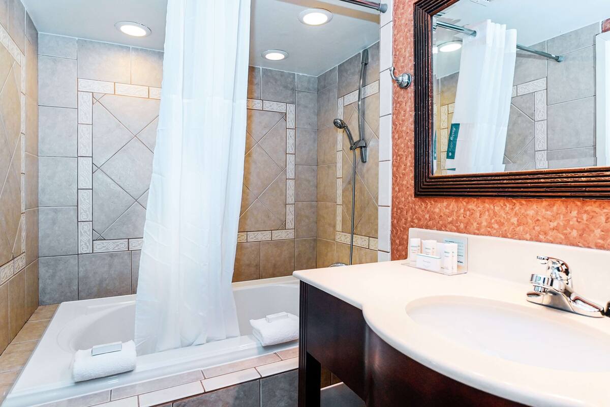 A modern bathroom with a bathtub, shower, and sink.