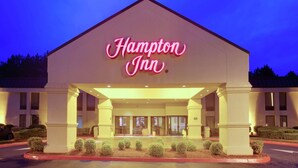 A Hampton Inn hotel with a prominent neon sign, a covered entrance, and a landscaped front with trimmed bushes. - Hampton Inn by Hilton Chester South (Chester)