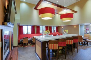 A spacious dining area with a large island, red and yellow pendant lights, and a red sofa.