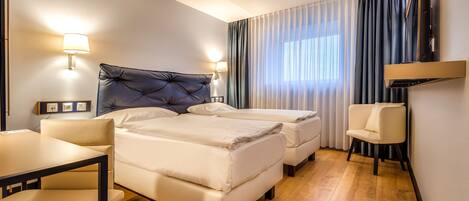 A hotel room with a large bed, a smaller bed, a desk, and a chair.