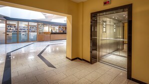 Un intérieur moderne doté d’un ascenseur en verre, d’un espace d’accueil et d’un vaste atrium baigné de lumière naturelle.