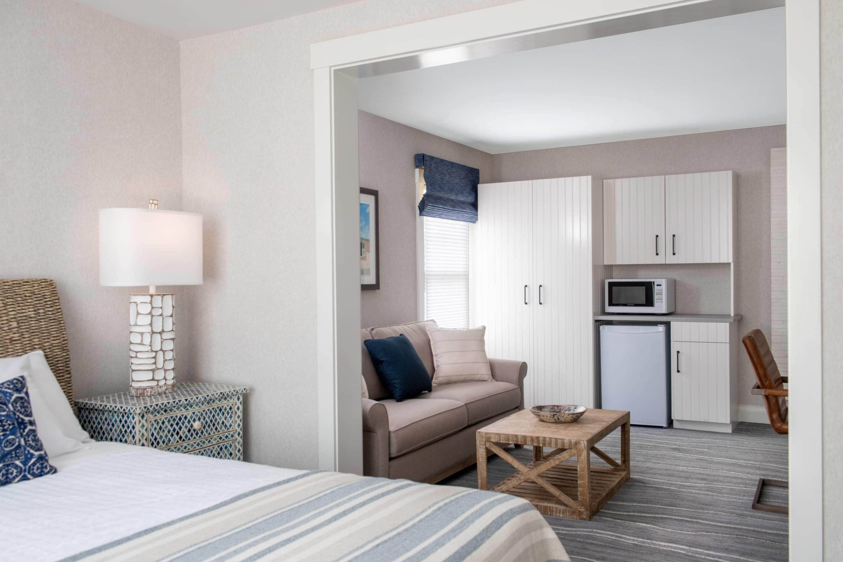 Una habitación de hotel con cama, mesita de noche, mesa de centro, sofá, microondas y refrigerador.