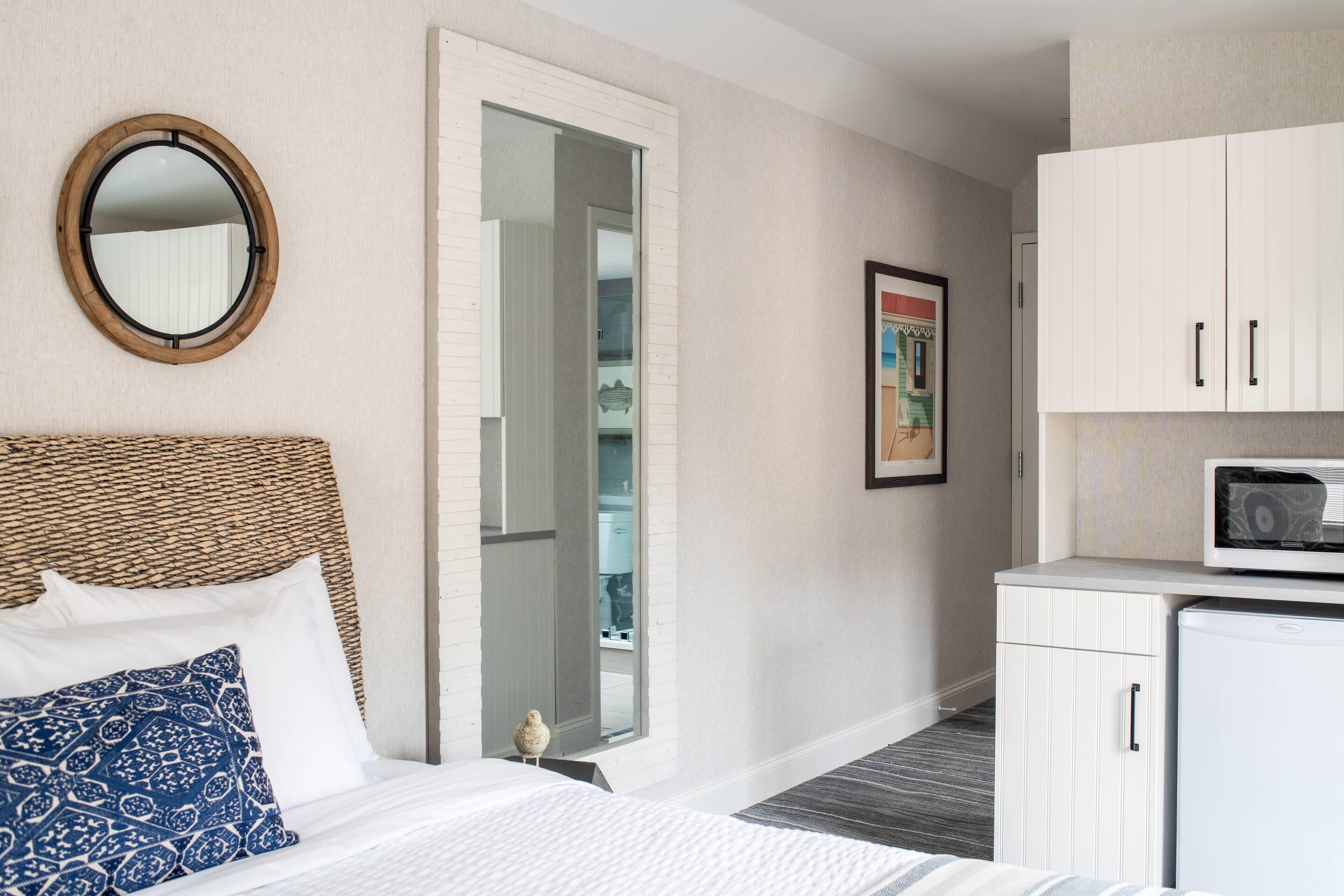 A hotel room with a bed, a wardrobe, a microwave, and a mirror.