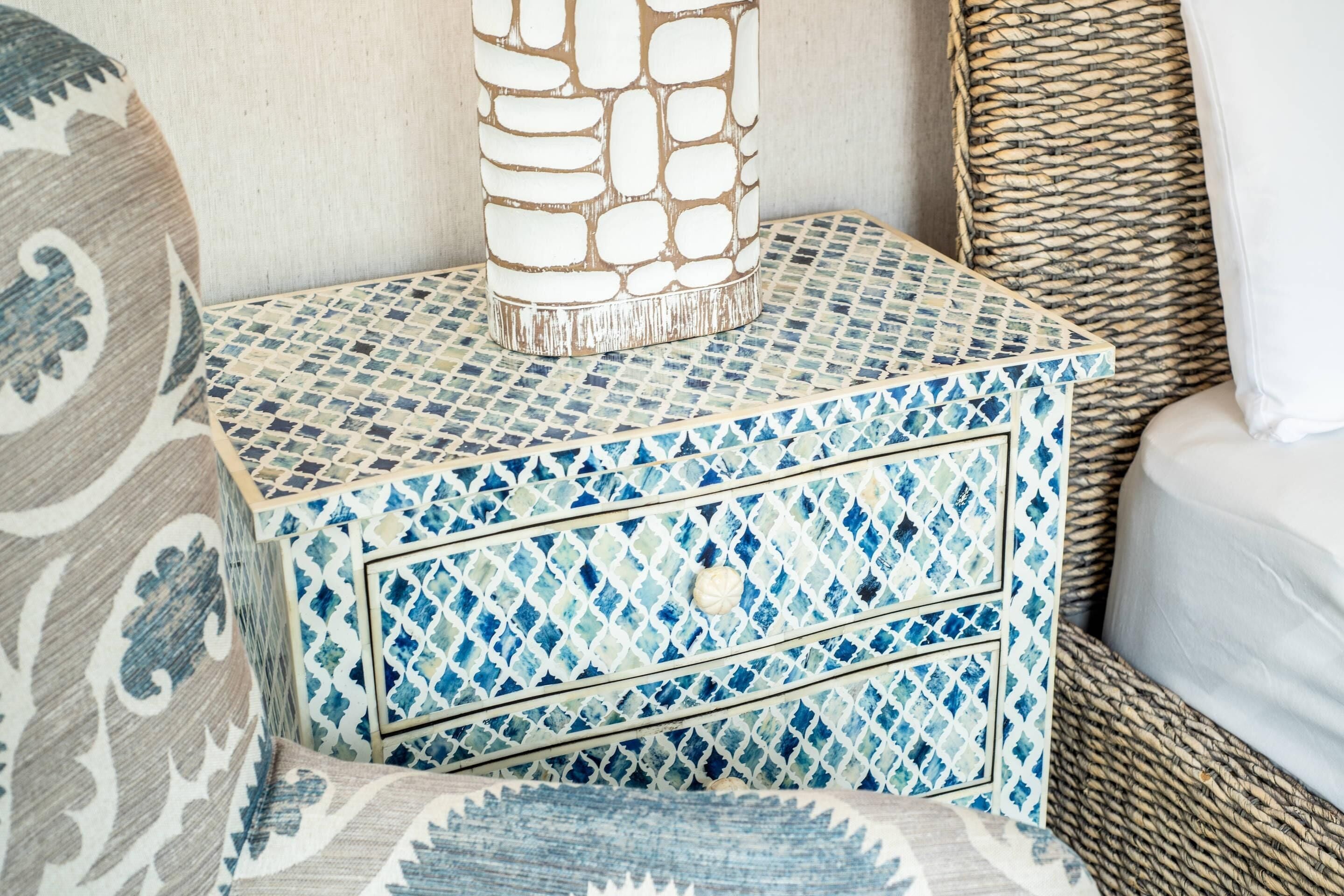 A decorative box with a blue and white geometric pattern, placed on a woven basket.