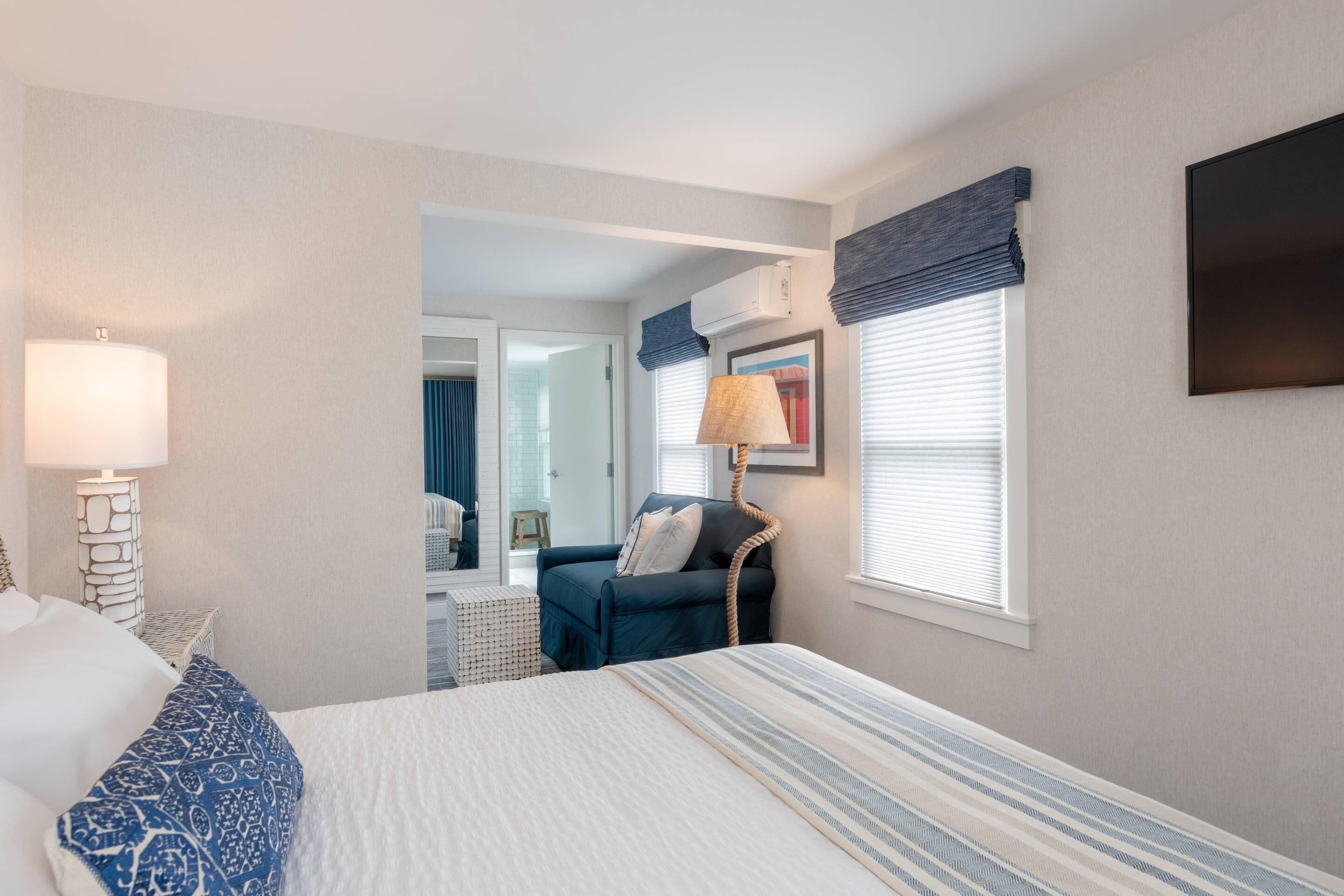 Une chambre d’hôtel avec un lit, une chaise, une lampe et un téléviseur.
