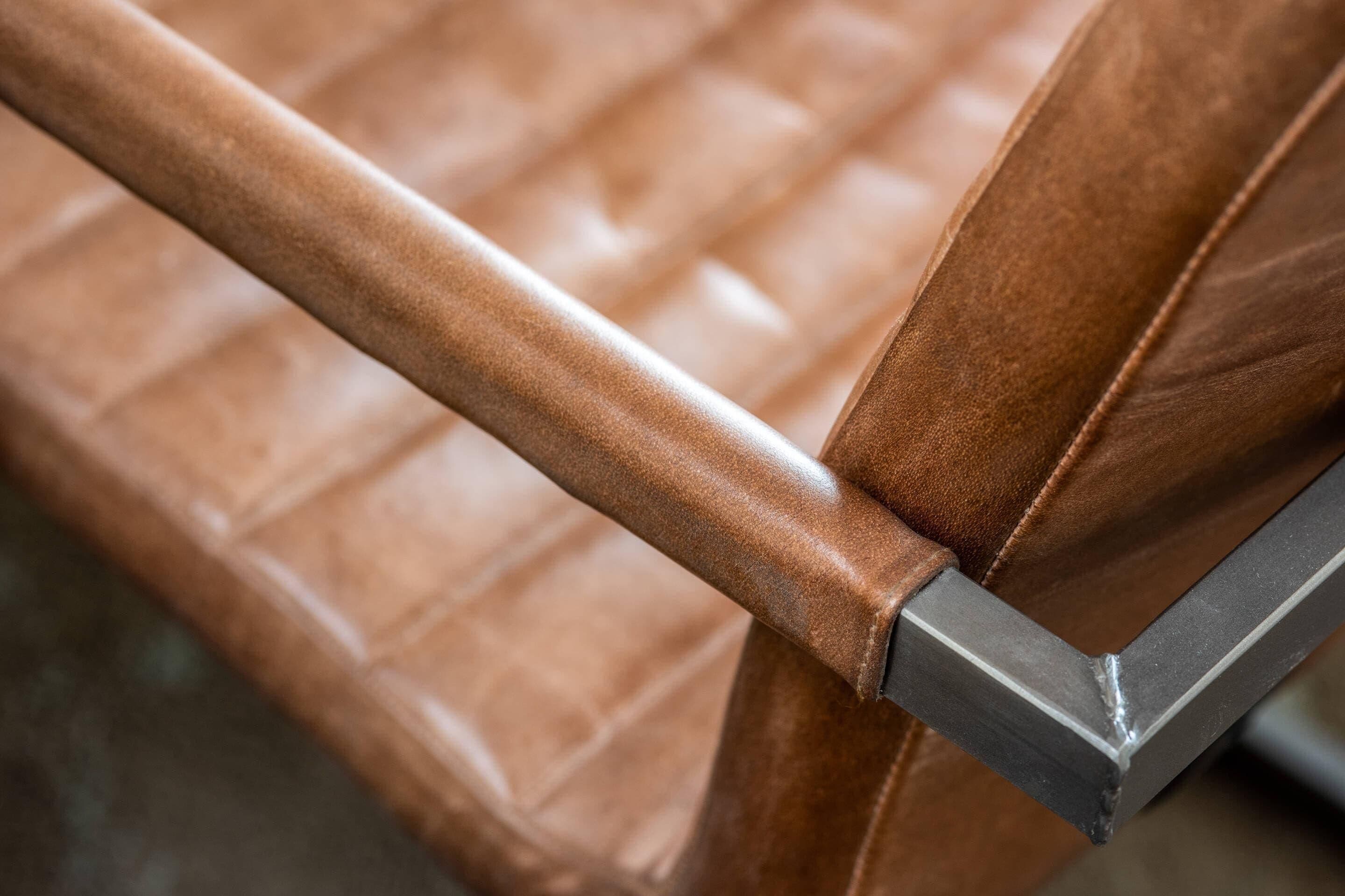 A close-up of a chair with a metallic frame and a textured brown seat.