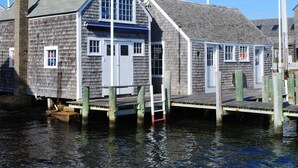 A wooden dock extending into a body of water, with a building featuring a gabled roof and white trim. - Edgar Hotel Martha's Vineyard, an Ascend Collection Hotel (Edgartown)