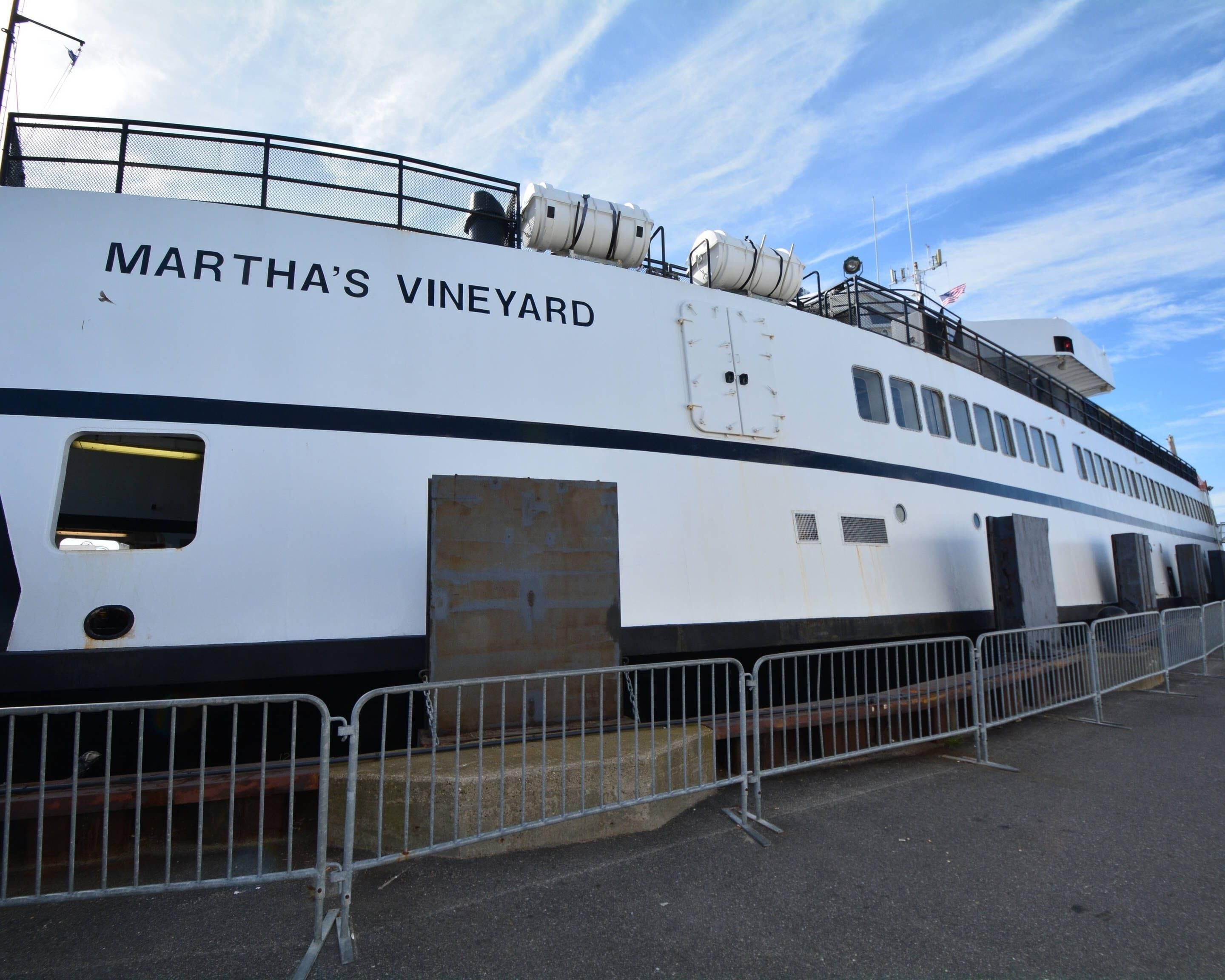 A large white ship named 'Martha's Vineyard' docked at a port with a clear sky in the background.