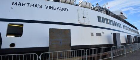 A large white ship named 'Martha's Vineyard' docked at a port with a clear sky in the background.