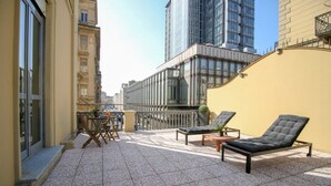A rooftop terrace with two lounge chairs, a small table, and a view of a tall building. - Hotel Diplomatic (Turin)
