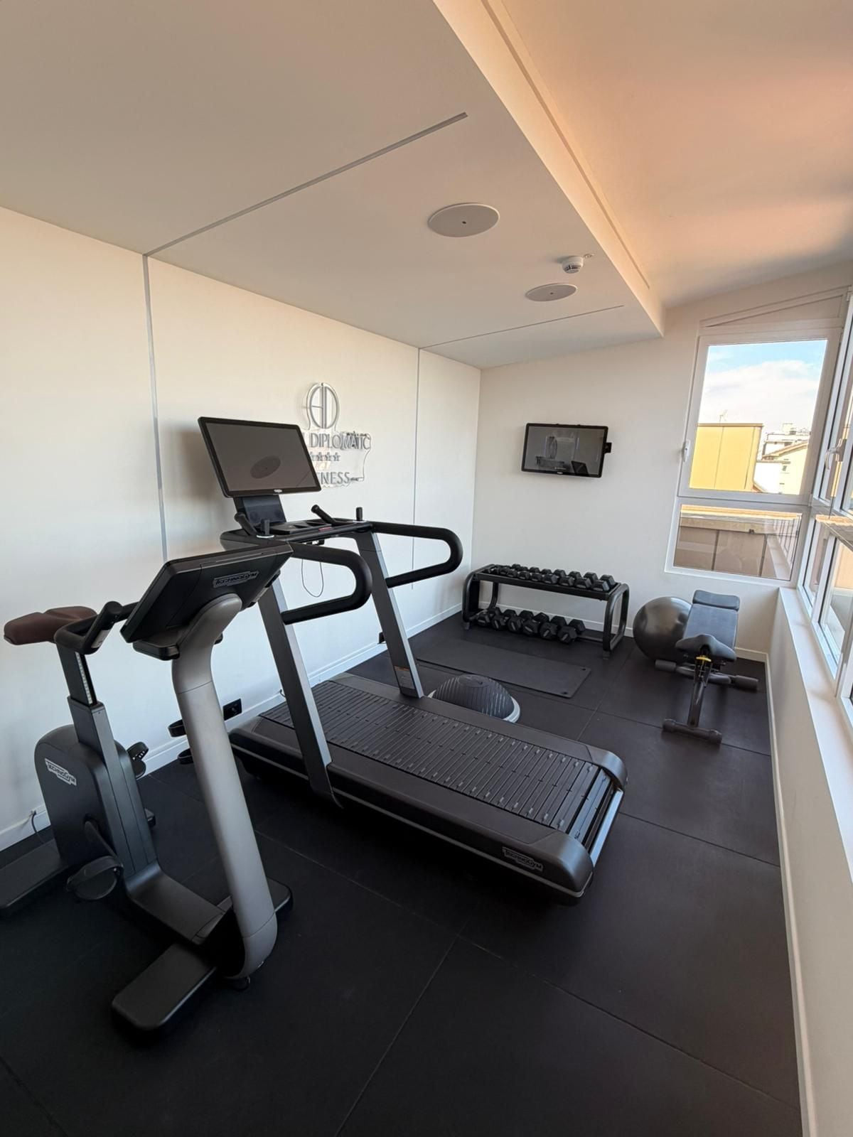 Een sportschool met een loopband, gewichten en trainingsapparatuur.