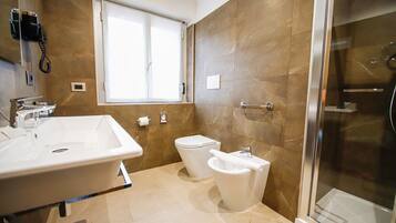 Ein modernes Badezimmer mit großem Waschbecken, Toilette, Bidet und Duschkabine aus Glas.