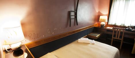 Una habitación de hotel con una cama, un escritorio, una silla, una lámpara y una ventana con cortinas.