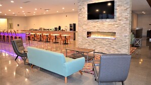 A spacious lobby with a stone fireplace, comfortable seating, a bar area, and a flat-screen TV mounted on the wall. - Richland Riverfront Hotel and Conference Center, Ascend Hotel Collection (Richland)