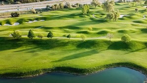An aerial view of a golf course with sand bunkers, water hazards, and trees. - Richland Riverfront Hotel and Conference Center, Ascend Hotel Collection (Richland)