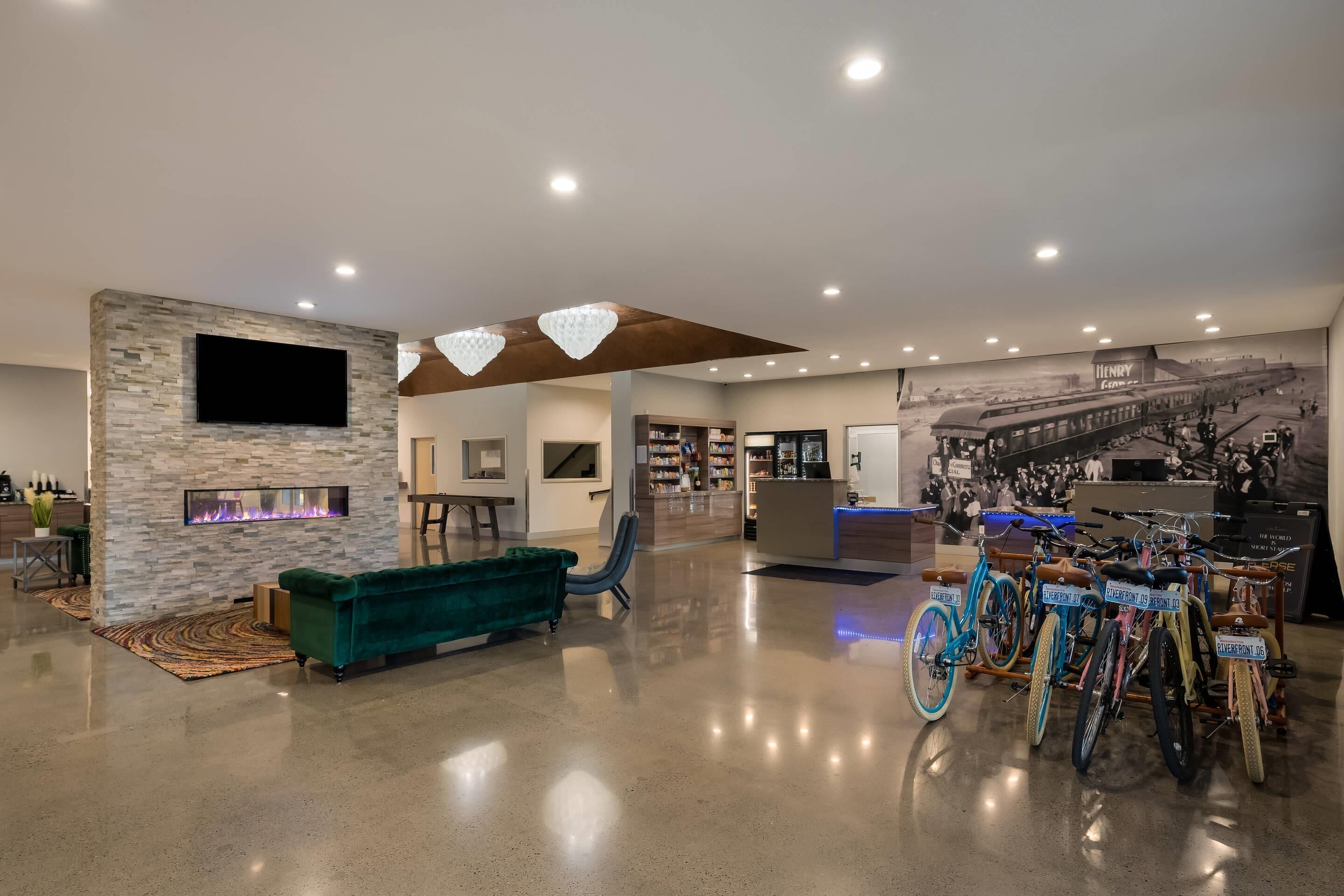 A spacious lobby with a stone wall, a fireplace, a green sofa, and a bike display.