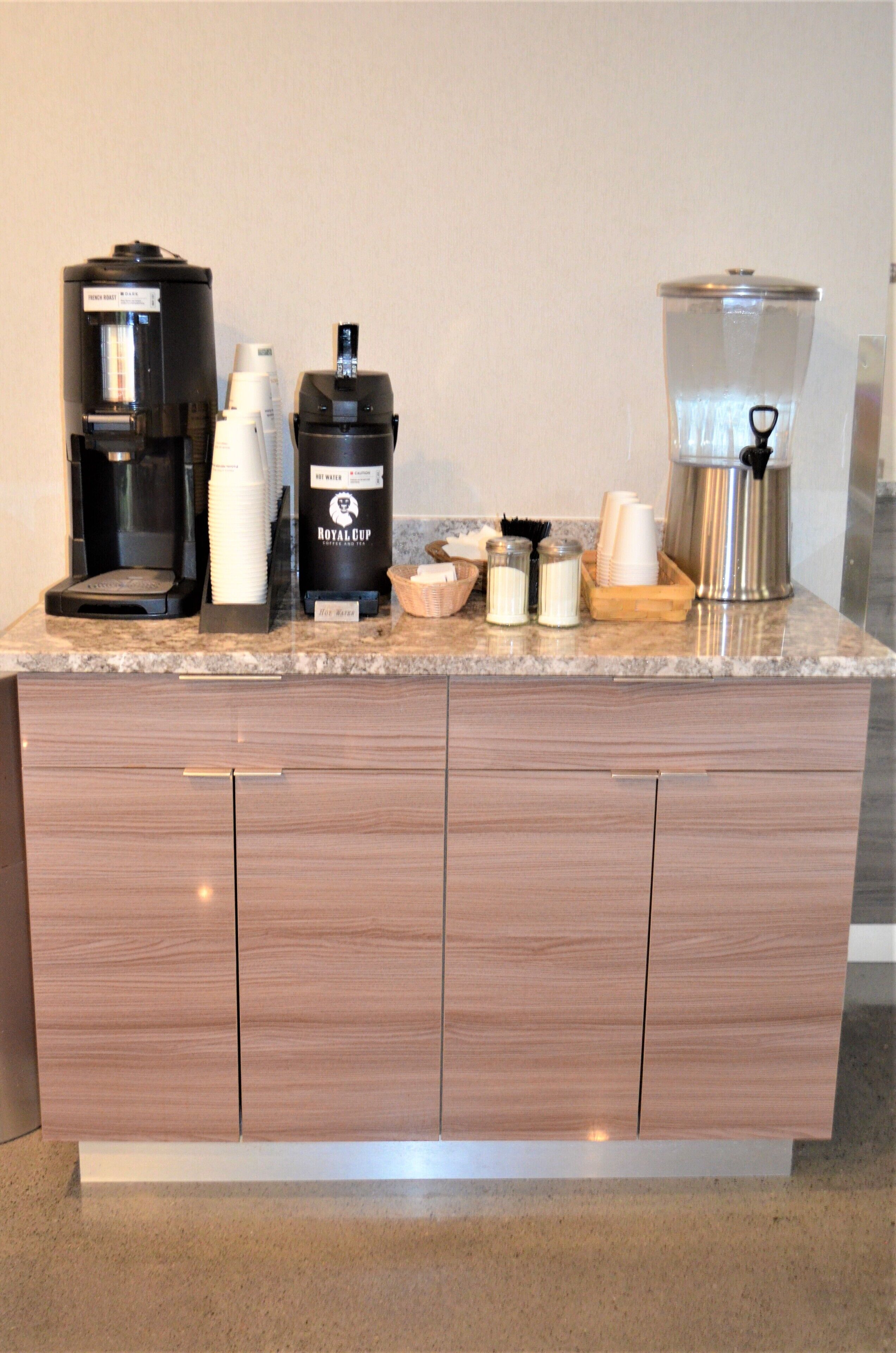 A kitchen counter with a coffee maker, a water dispenser, a coffee pot, and a food warmer.