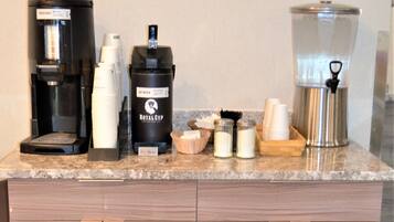 A kitchen counter with a coffee maker, a water dispenser, a coffee pot, and a food warmer.
