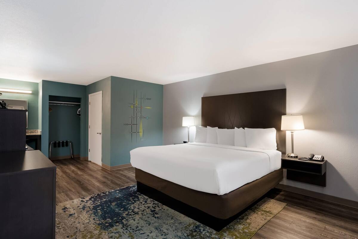 Ein modernes Hotelzimmer mit einem großen Bett, Nachttischlampen, einem Kleiderschrank und einem Badezimmer.