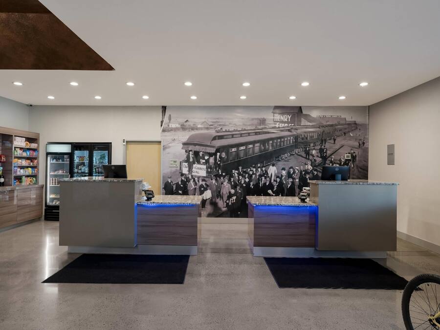 A reception area with a large historical mural, a counter, and a refrigerator.