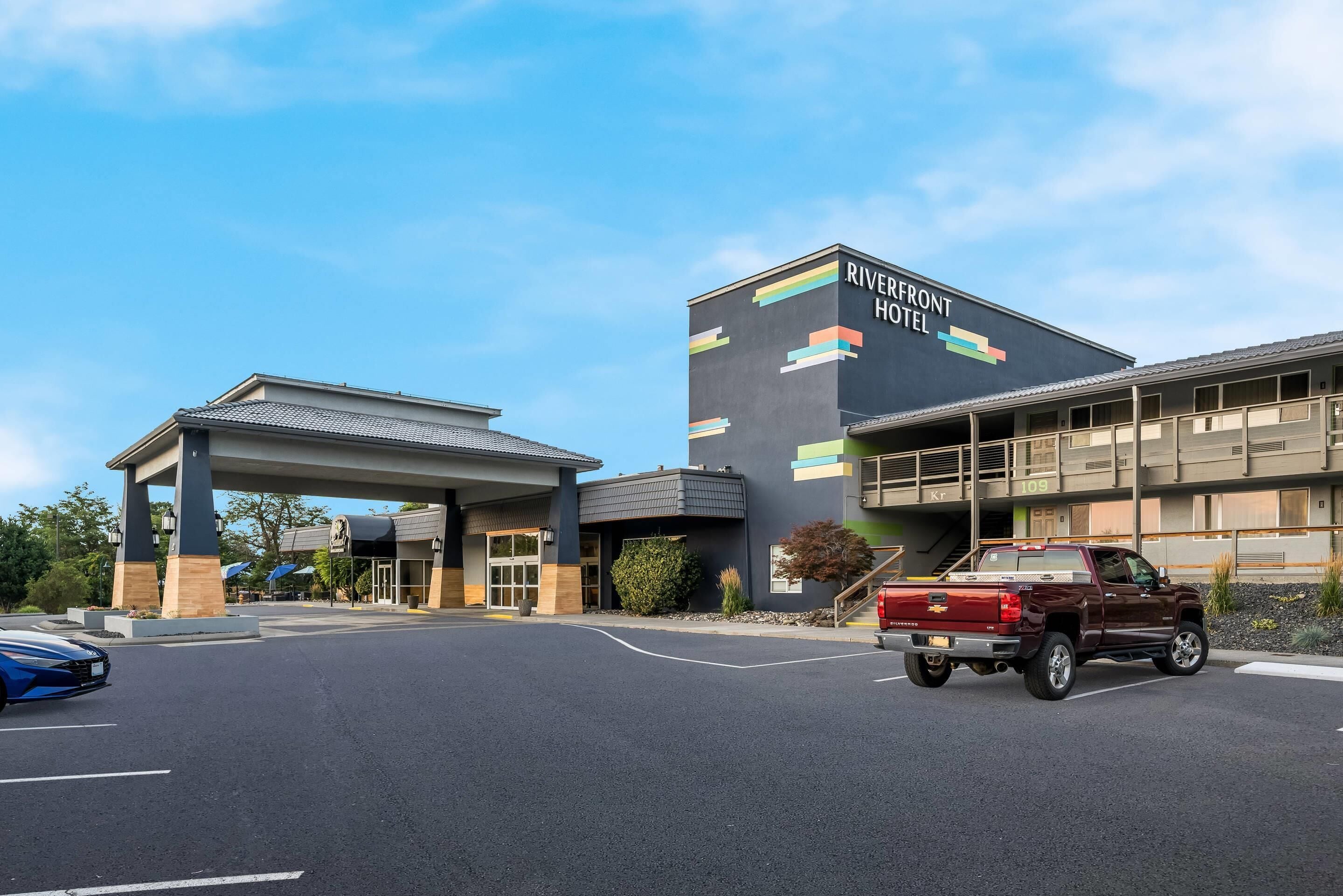 A hotel entrance with a covered driveway and a parking lot.
