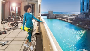 A person on a balcony overlooking a body of water with exercise equipment and a view of a bridge and buildings. - Sheraton Grand Chicago Riverwalk (Chicago)