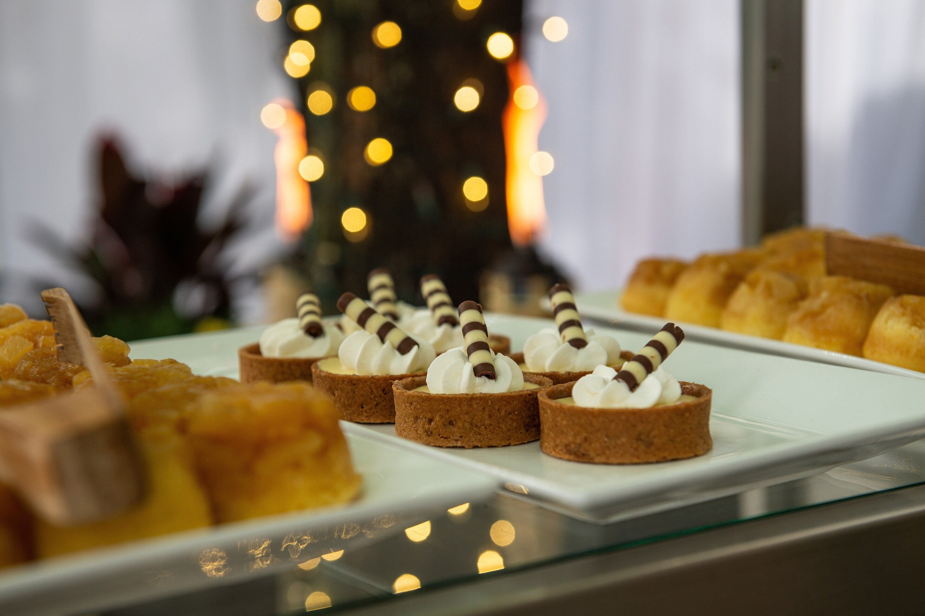Una mesa con varios pasteles y un árbol decorativo al fondo.