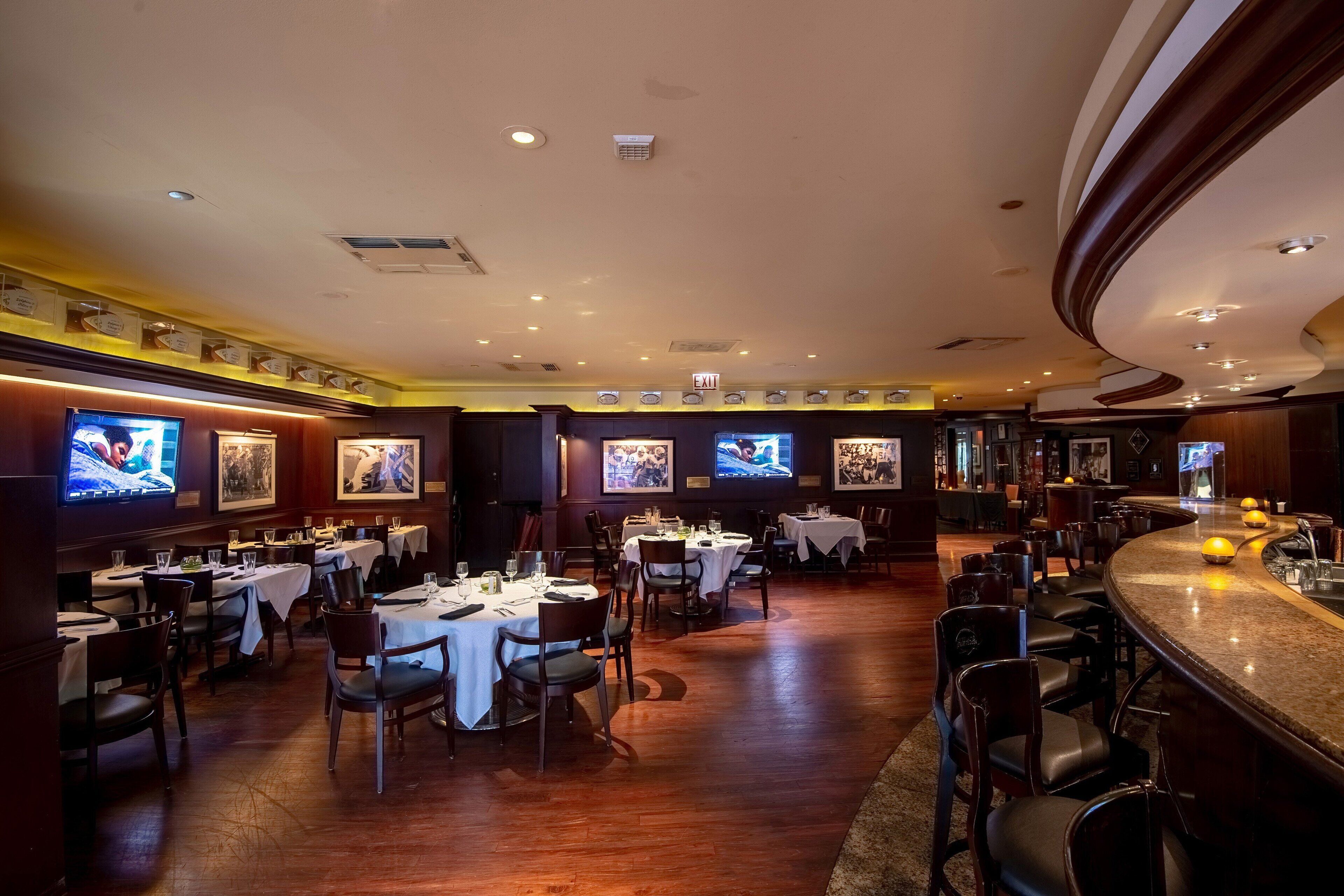 Un restaurant doté de nombreuses tables et chaises, d’un bar et de plusieurs téléviseurs diffusant différents programmes.