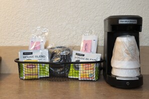 A coffee maker and a basket of coffee pods on a countertop.