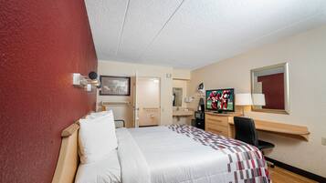 A hotel room with a bed, a desk, a television, and a mirror.