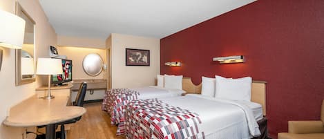 A hotel room with two beds, a desk, a chair, a TV, and a mirror.