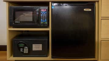 Una cocina equipada con microondas, refrigerador pequeño y una caja fuerte.
