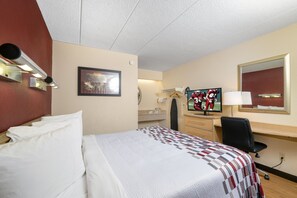 A hotel room with a bed, a desk, a chair, a television, and a mirror.
