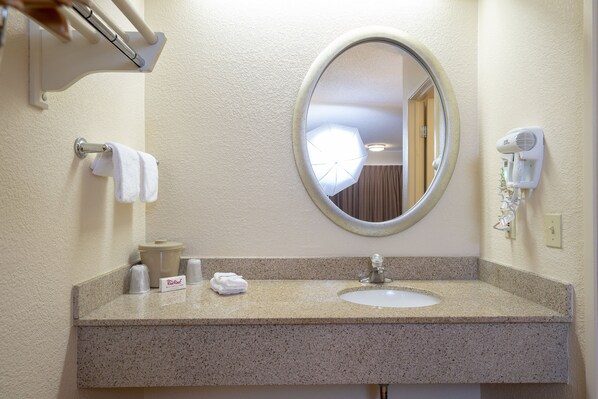 A bathroom with a sink, mirror, towel rack, and a hairdryer mounted on the wall.