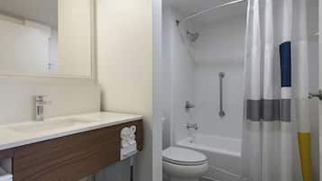 Een badkamer met een witte wasbak, een spiegel, een toilet en een douche met een gebogen glazen deur.