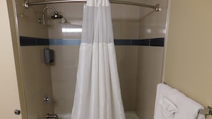 A shower with a glass door, a handheld showerhead, and a white curtain.