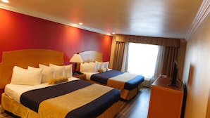 A hotel room with two beds, a desk, and a window with curtains.