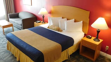 A hotel room with a large bed, two bedside lamps, a wooden nightstand, a telephone, and a chair.