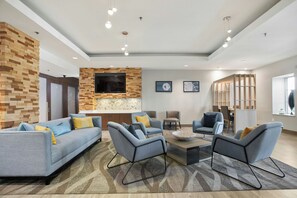 A modern living room with a built-in TV, comfortable seating, and a decorative wall.