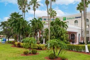 Un hotel Holiday Inn Express con un giardino curato, palme e una fontana.