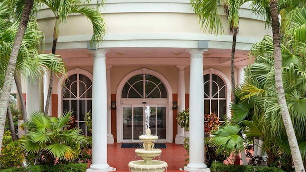 A hotel with a central fountain, palm trees, and a red pathway leading to the entrance. - Holiday Inn Express Miami Airport Doral Area by IHG (Miami)