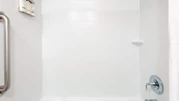 Un baño con paredes de azulejos blancos, una ducha y un inodoro.