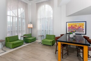 Un soggiorno moderno con divani verdi, un tavolo da pranzo in vetro e un'opera d'arte colorata appesa al muro.
