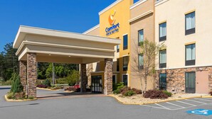 Un hôtel Comfort Inn & Suites doté d’une entrée abritée, de piliers en pierre et d’un parking comprenant des places réservées aux personnes handicapées.
