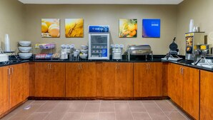 Une cuisine d’hôtel avec des armoires en bois, un réfrigérateur et divers produits alimentaires disposés sur le plan de travail.